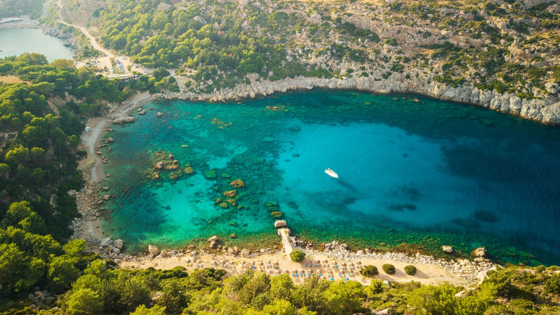 Aerial view of a small boat on open water near a rocky coastline